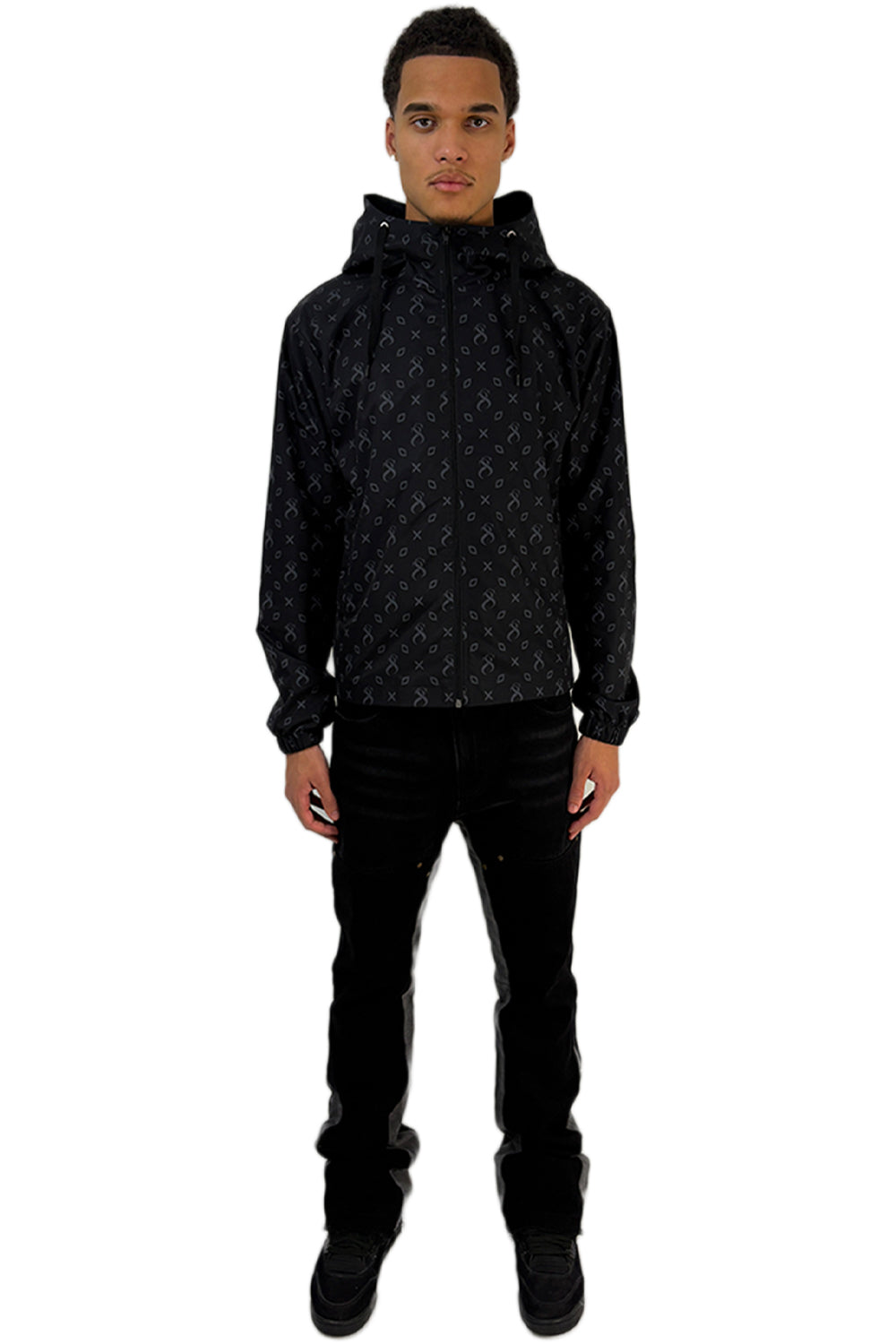  Model trägt eine Midnight Windbreaker mit durchgehendem Muster und modernem Design, kombiniert mit einer schwarzen Hose.