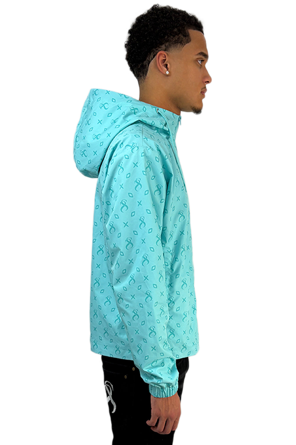 Model trägt die Windjacke „Caribbean Bay“ in Türkis mit charakteristischem Sterlingz-Muster über die gesamte Fläche.
